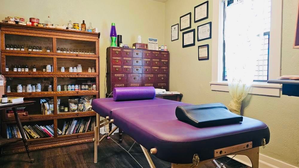 There is a purple massage table in the middle of the room.