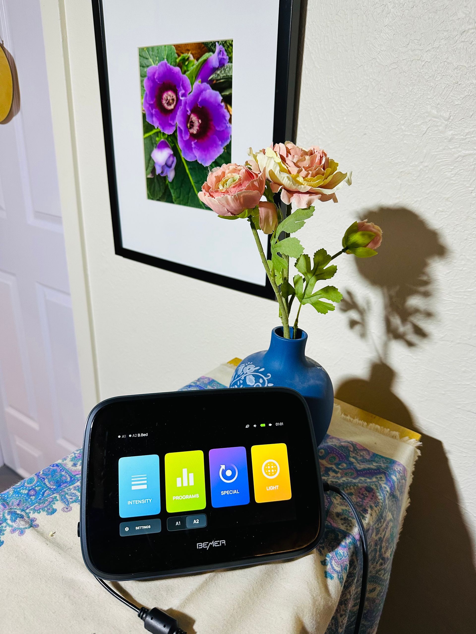 A tablet is sitting on a table next to a vase of flowers